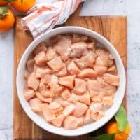 Chunks of chicken breasts and thighs boneless cut int 1 inch cubes in a plate