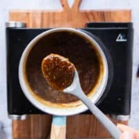 Orange sauce thickened and ready, and a spoon showing the consistency of it