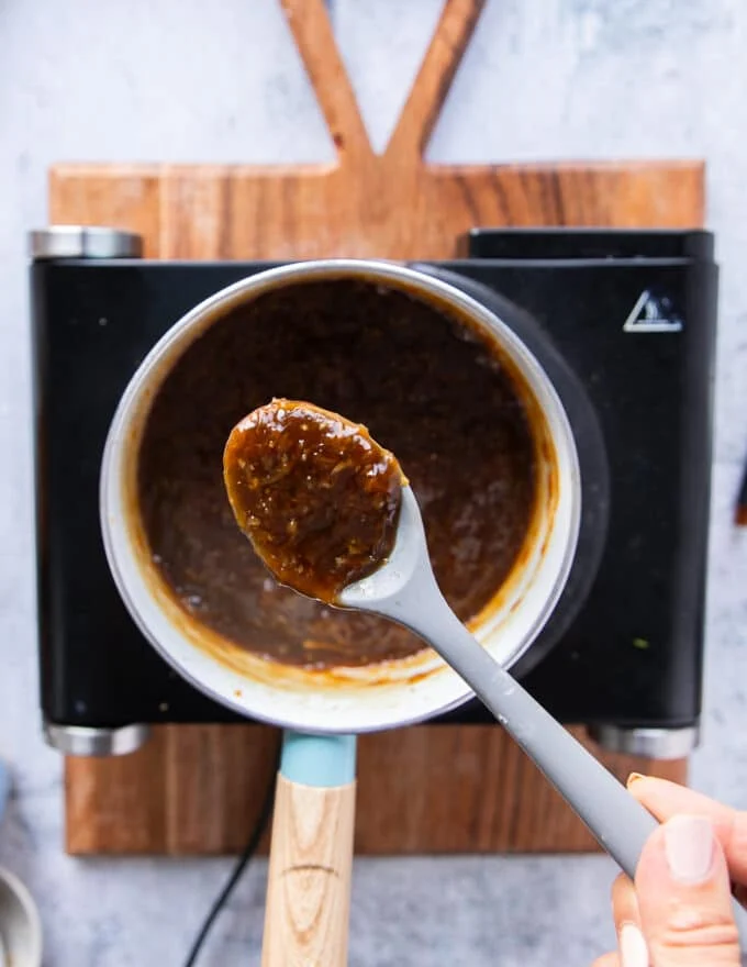 Orange sauce thickened and ready, and a spoon showing the consistency of it