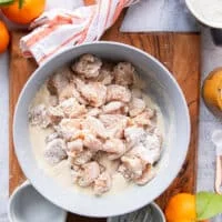 The cut up chicken chunks in a bowl tossed with some cornstarch to help stick to the batter
