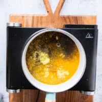 A small pot with all the sauce ingredients added in at once including orange juice and zest, grated garlic and ginger, soy sauce, brown sugar, rice vinegar