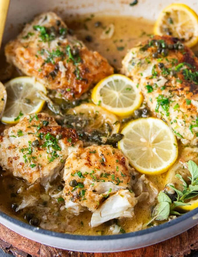 A broken up and flaked piece of cod in the pan and sauce showing how flakey the cod recipe is