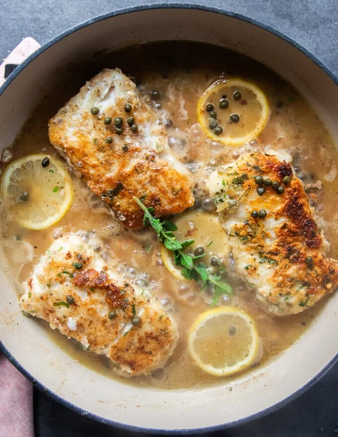 The stock and wine are added to the same pan of the golden cod fish and simmering