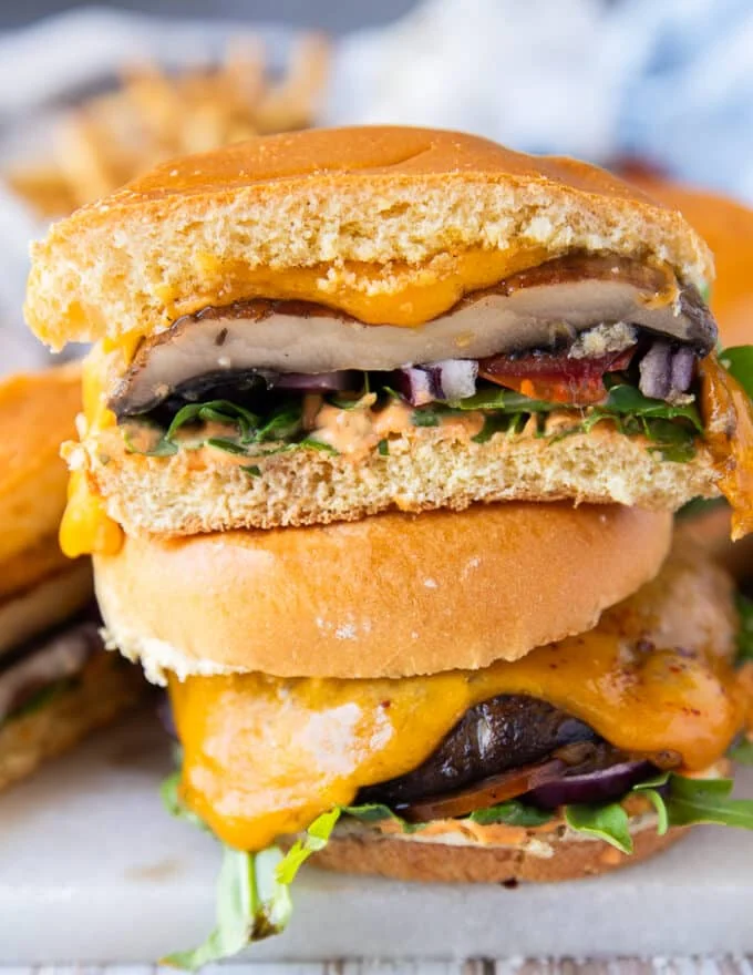 A stack of a cut up portobello mushroom cross wise to show the texture and layers of sauce and toppings in the burger close up