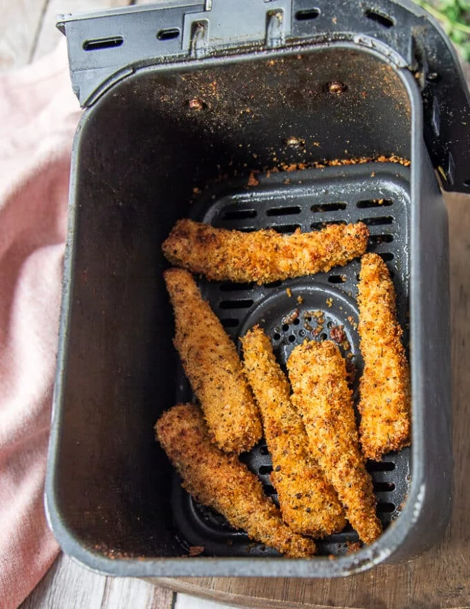 Fish Fingers in an air fryer basket perfectly cooked and golden.