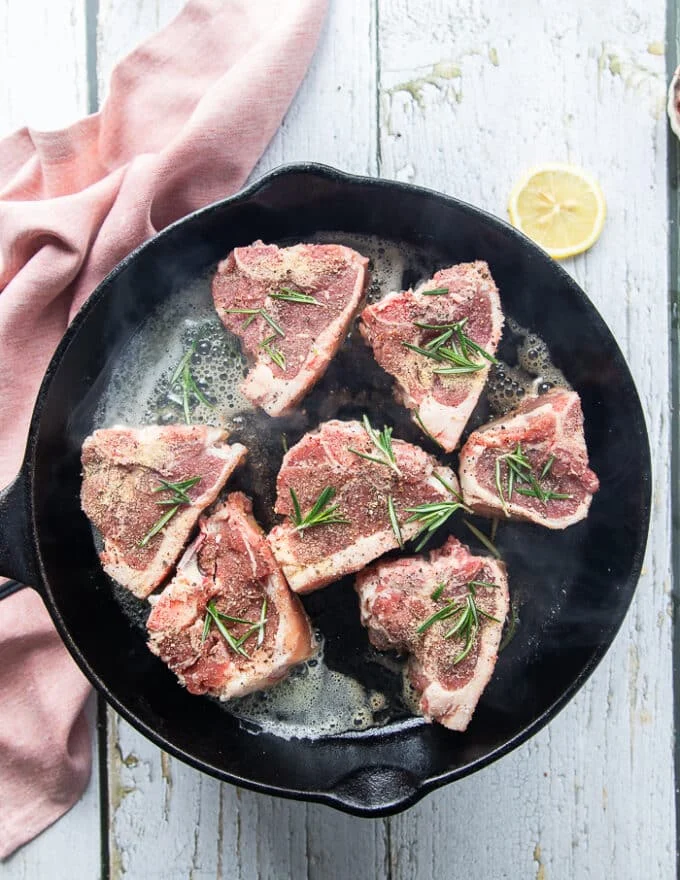 lamb loin chops placed on a heavy duty cast iron pan in a single layer
