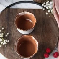 Two ramekins perfectly coated in butter and cocoa powder on a wooden tray