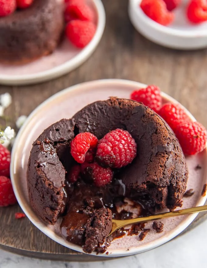 A hand scooping out a spoonful of the cooked molten lava cake recipe showing the cake and the truffle center eaten together