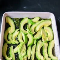 Avocado slices are arranged on top of the seaweed sheet in the baking pan