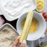 The zucchini fries coated in egg mixture as the second stage of breading