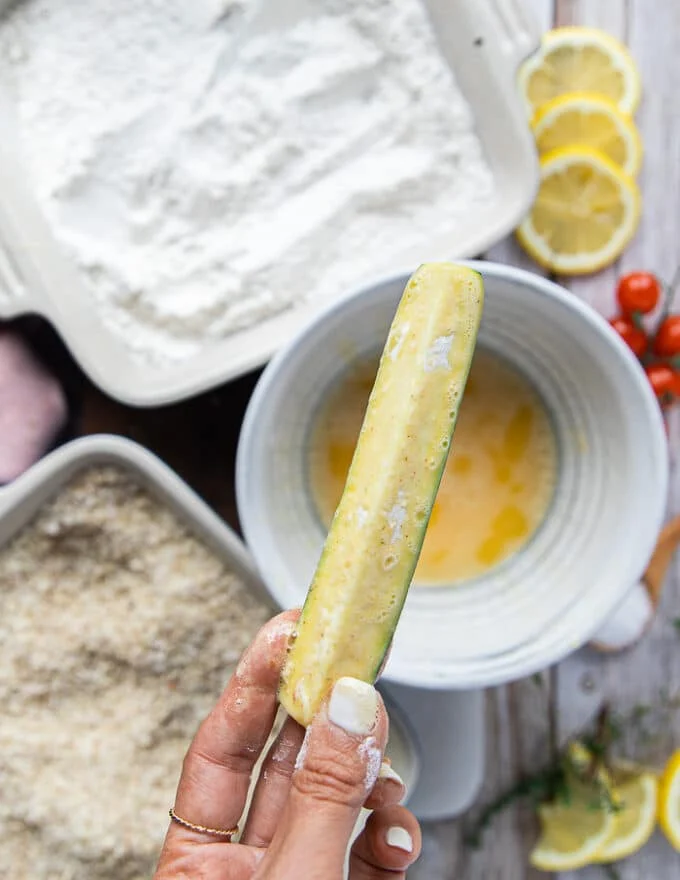 The zucchini fries coated in egg mixture as the second stage of breading