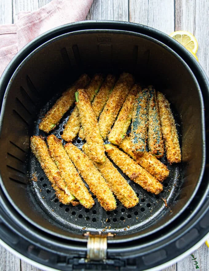golden and perfect air fryer zucchini fries in the basket of the air fryer