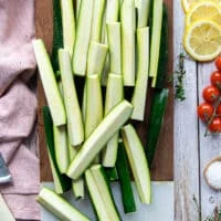 Zucchini cut into fries shape on a wooden board