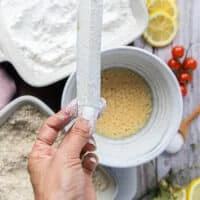 A hand holding the zucchini fries that has been dipped in the flour and shaken off.