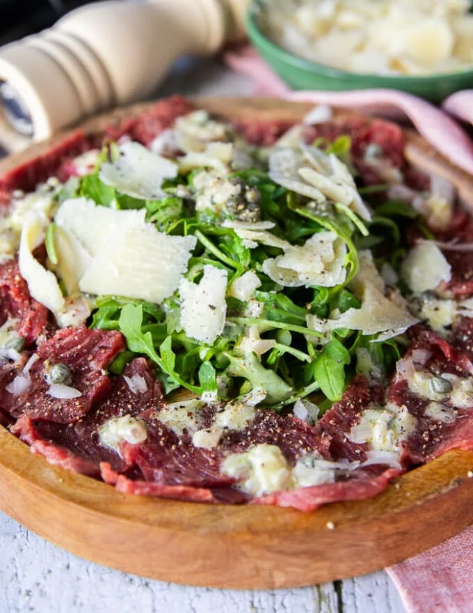 side view of a beef carpaccio showing the layers of beef and dressing