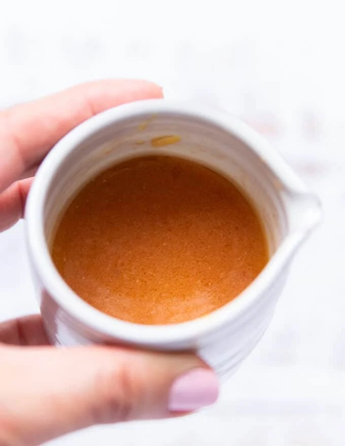A hand holding a jar with the honey citrus dressing mixed together