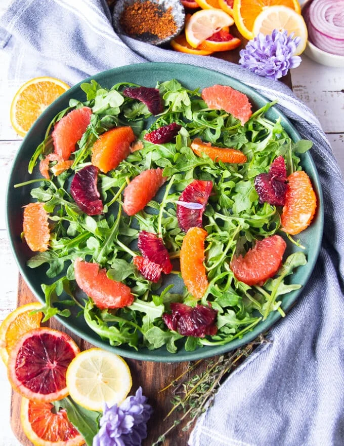 Layering the halloumi salad on a plate with arugula as a base, and some orange segments, blood oranges, and grapefruit