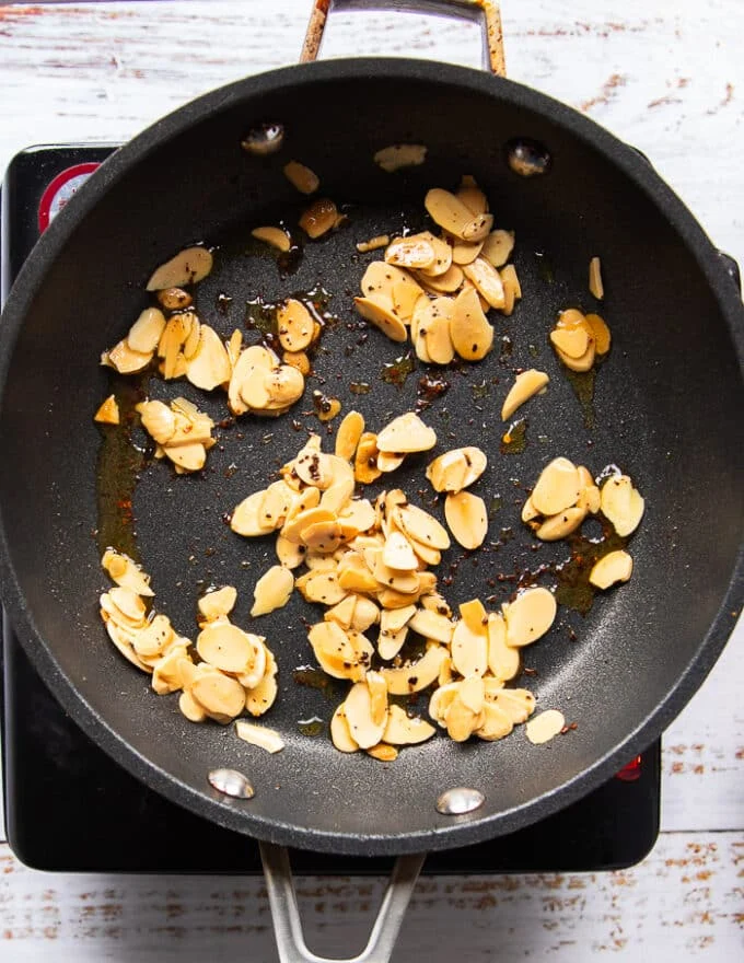 Golden toasted slivered almonds in a pan with chilli flakes
