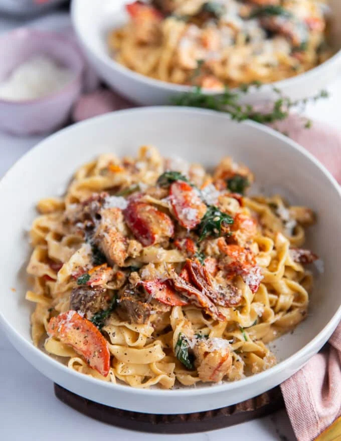 Side view close up of a plate of lobster pasta showing the creamy sauce and the succulent lobster