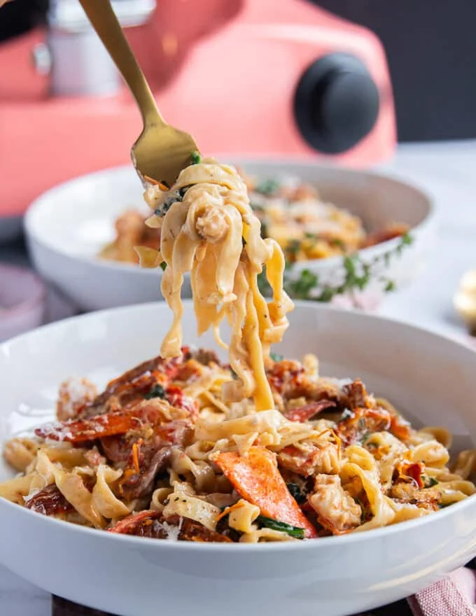 A fork stretching and eating the lobster pasta showing the creamy pasta with the lobster