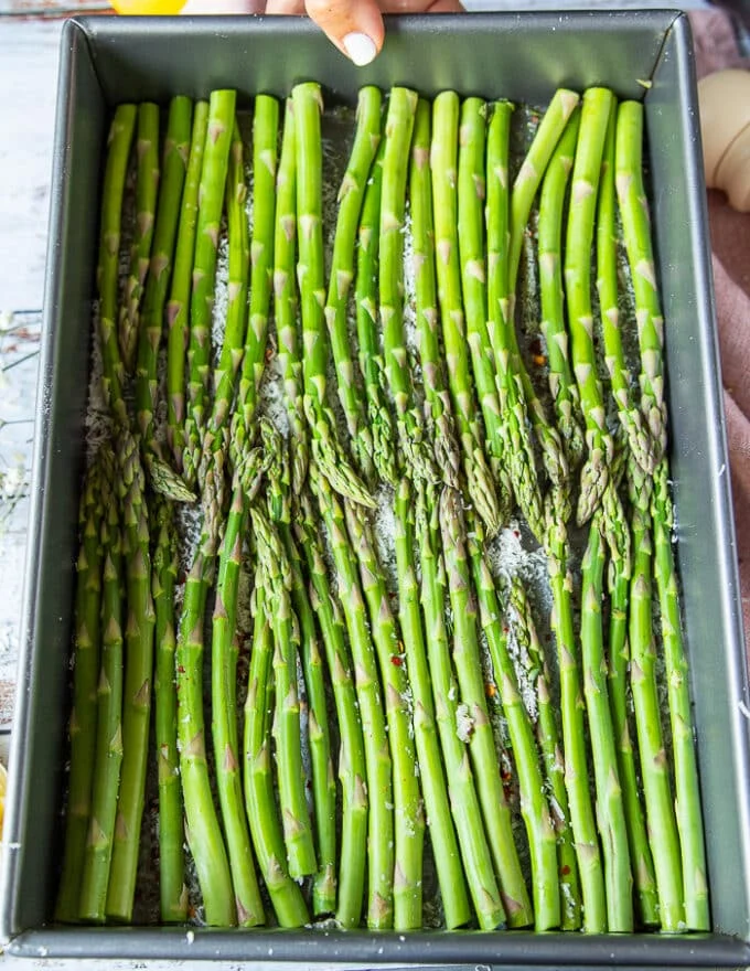 The trimmed asparagus arranged in a single layer over the baking sheet and ready to roast