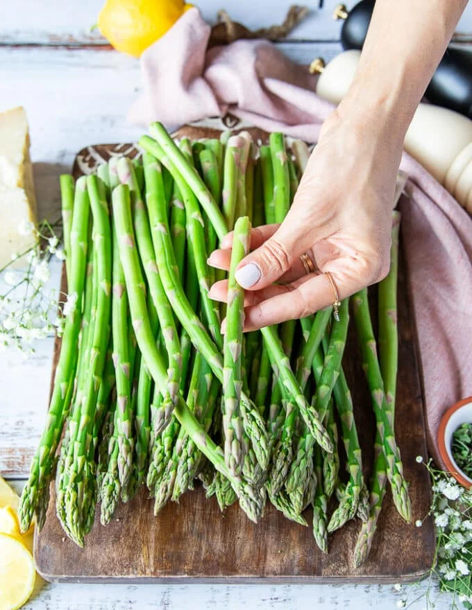 Prepping the asparagus for air frying, a hand holding one piece of asparagus and showing how to snap it