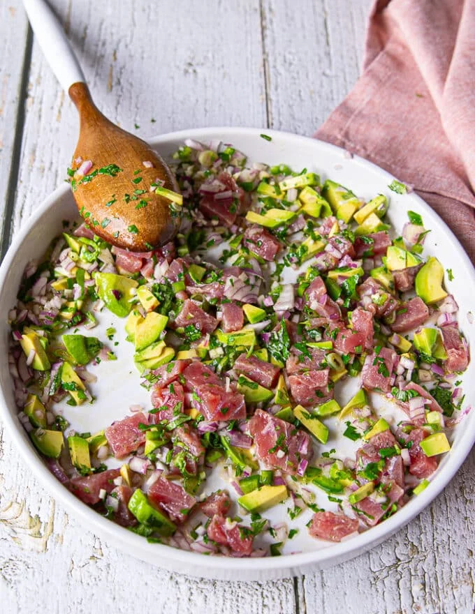 A wooden spoon mixing in all the ceviche recipe ingredients