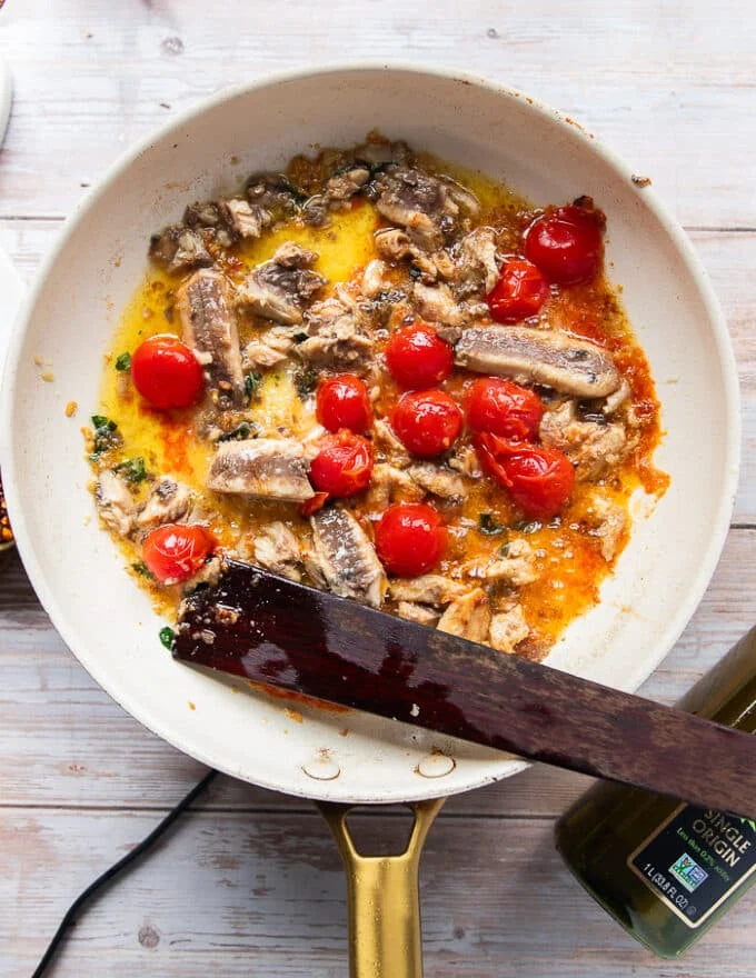 The sardines are then added here to the same skillet after the tomatoes have burst and the garlic has cooked