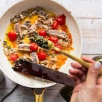 A hand adding in a spoonful of capers to the sauce pan