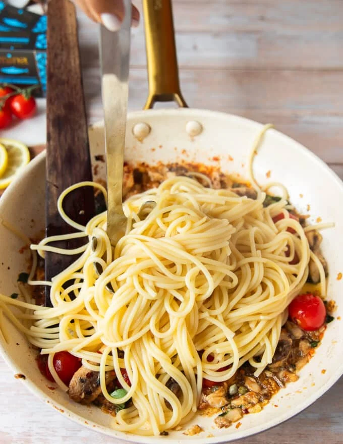 Cooked spaghetti is added to the sauce skillet