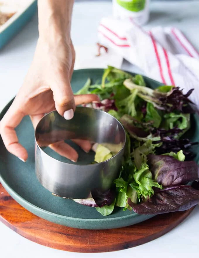 A hand holding a 3 inch round mold to use for shaping the steak tartare