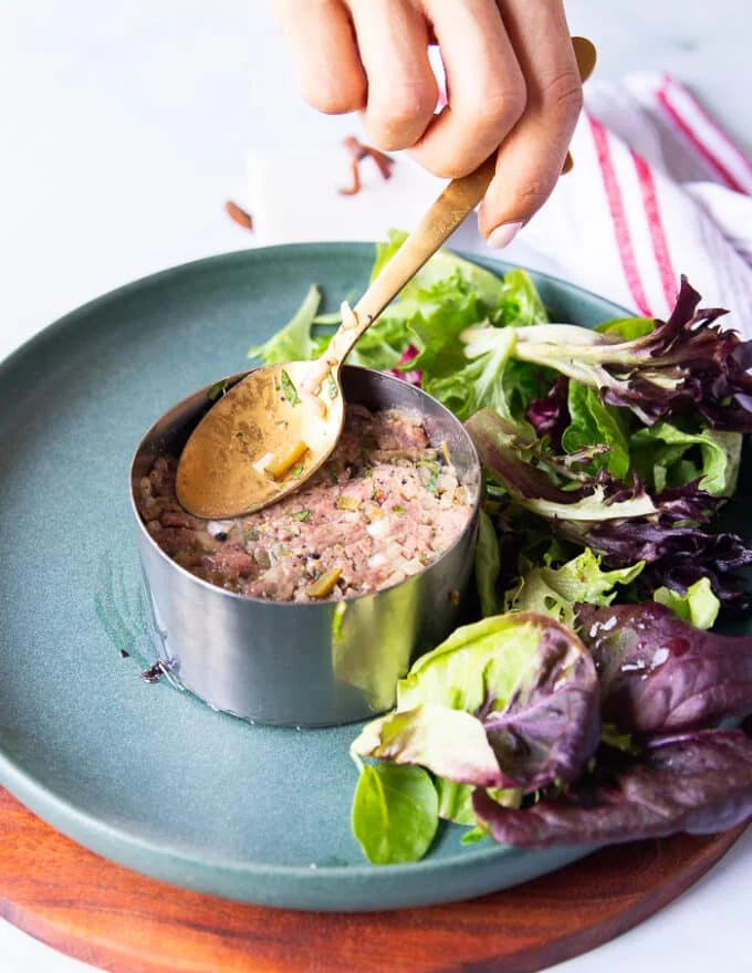 Spooning in the steak tartare mixture into the round mold and pressing the mixture well to hold the round shape