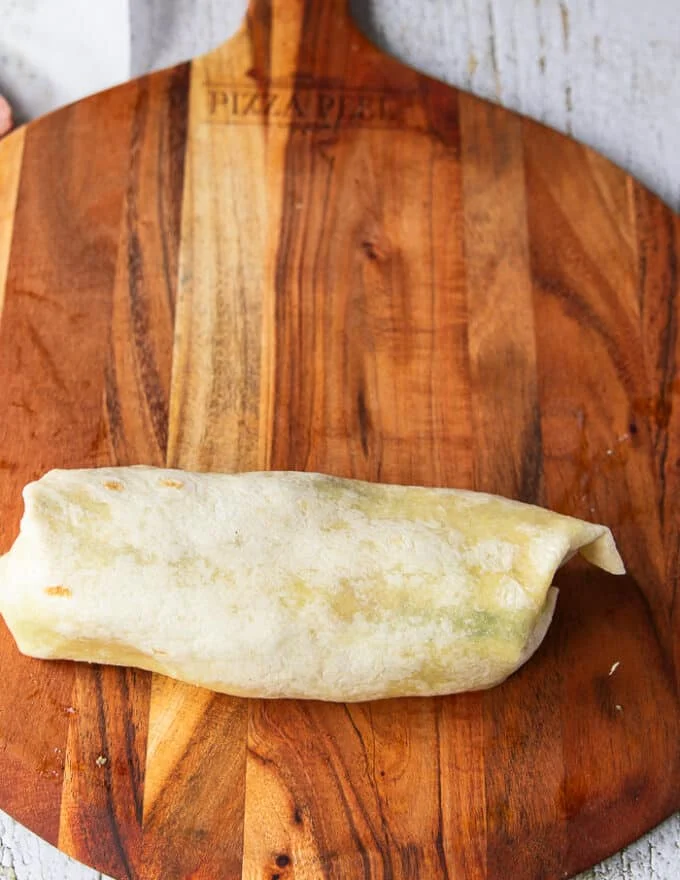 The final step is rolling the folded tortilla to complete the wrap