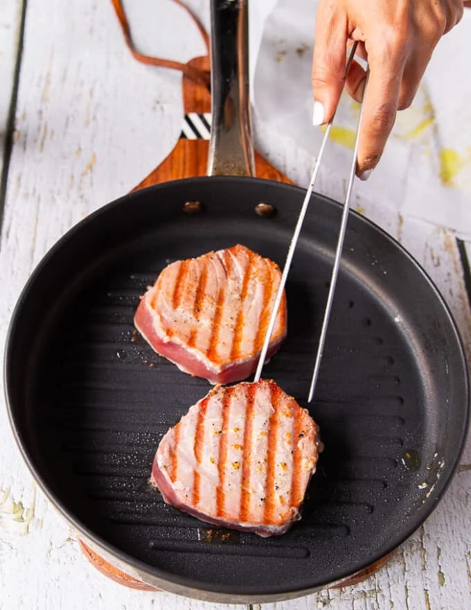 Perfect tuna steaks seared on one side, flipped to show the grill marks and continue cooking on the other side