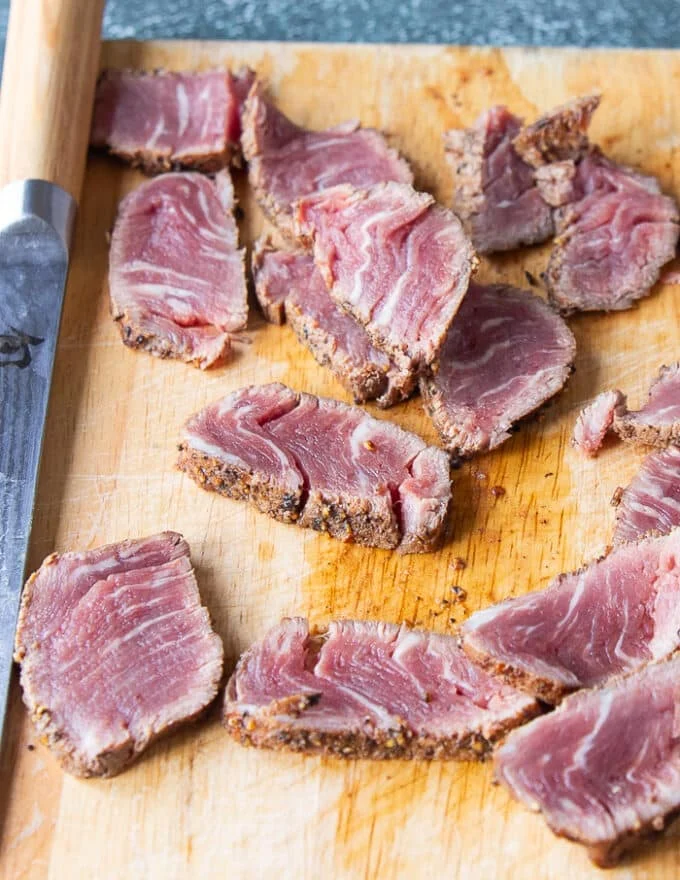 a sharp knife slicing the chilled tenderloin steak to make slices of beef tataki