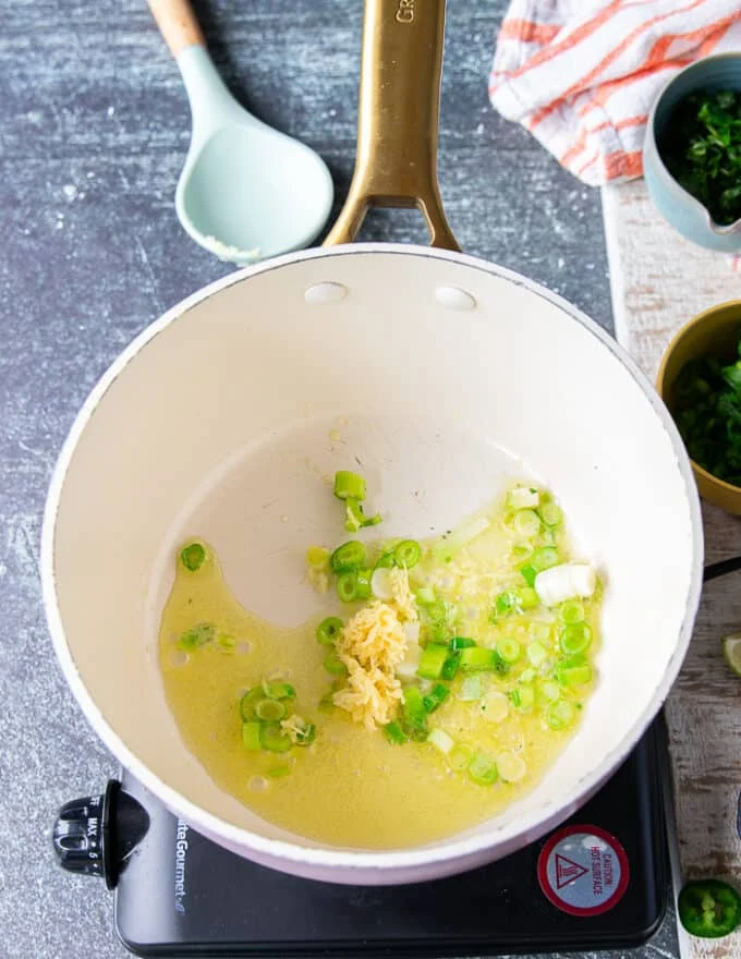 Scallions and garlic sautéing in olive oil in a pot to flavor the base of cilantro lime rice recipe