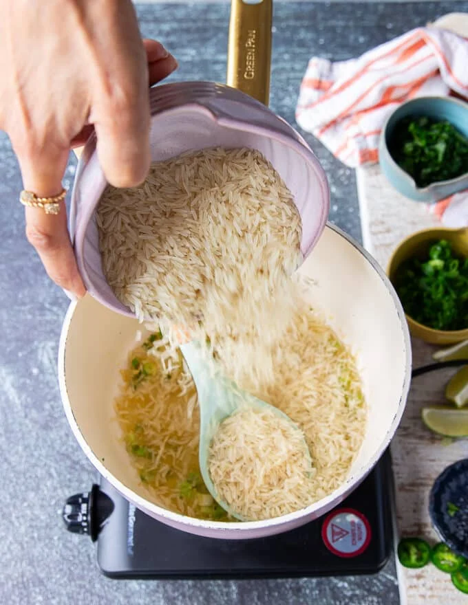 Long grain rice being added to the pot