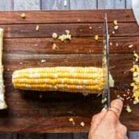 Demonstrating how to cut corn ribs by trimming the edges off the corn cob first