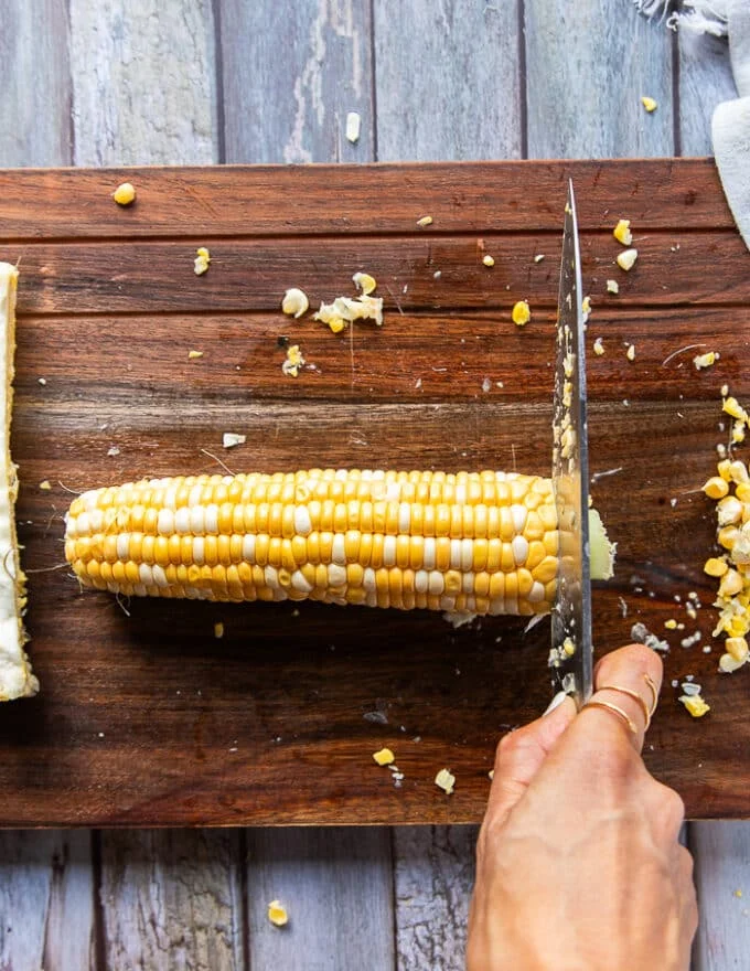 Demonstrating how to cut corn ribs by trimming the edges off the corn cob first