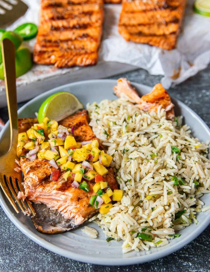 A fork cutting up the grilled trout showing how succulent and well grilled the fish is