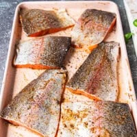 heavily oiled and seasoned rainbow trout fillets on a sheet ready to grill