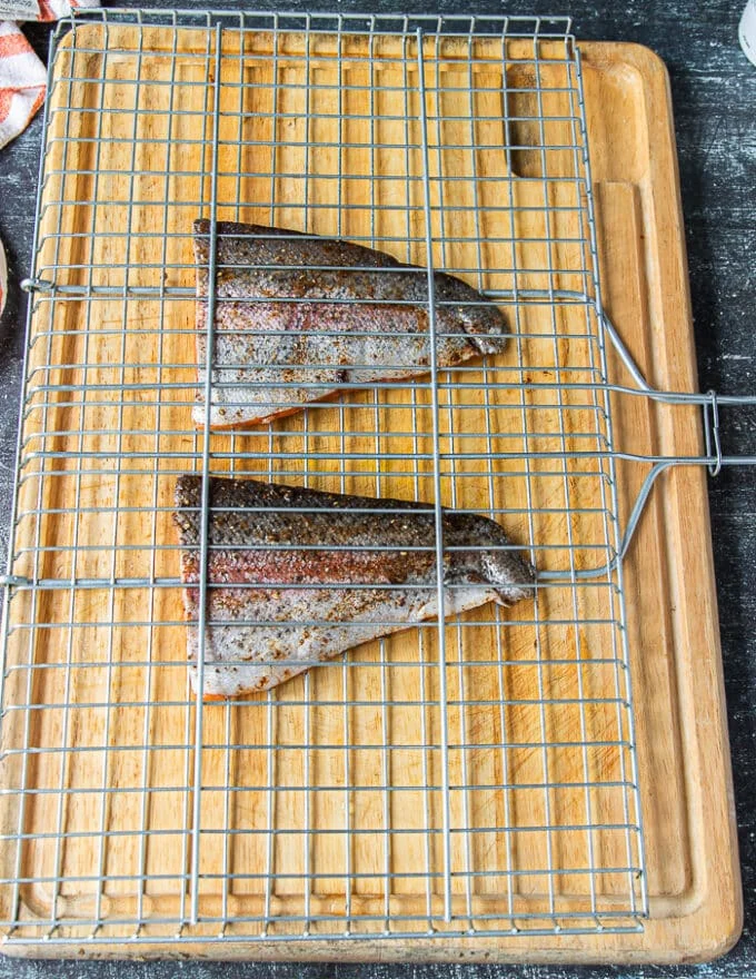 seasoned and oiled trout in the middle of a grill basket ready to grill