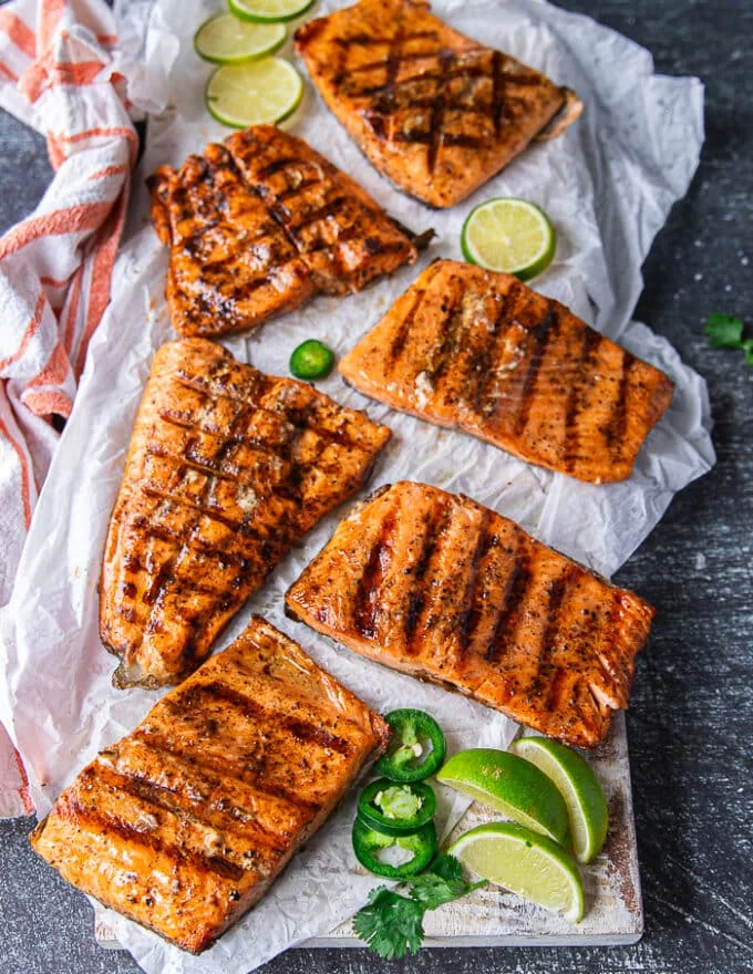 grilled trout on a board surrounded by lime and jalapeno