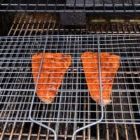 grill basket with trout on the grill over high heat ready to flip