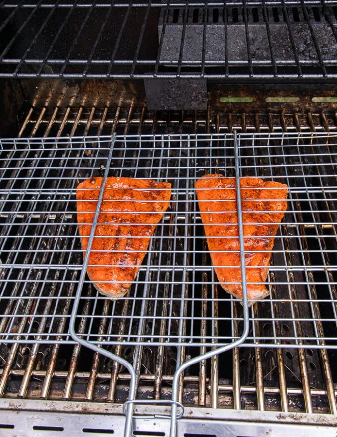 grill basket with trout on the grill over high heat ready to flip