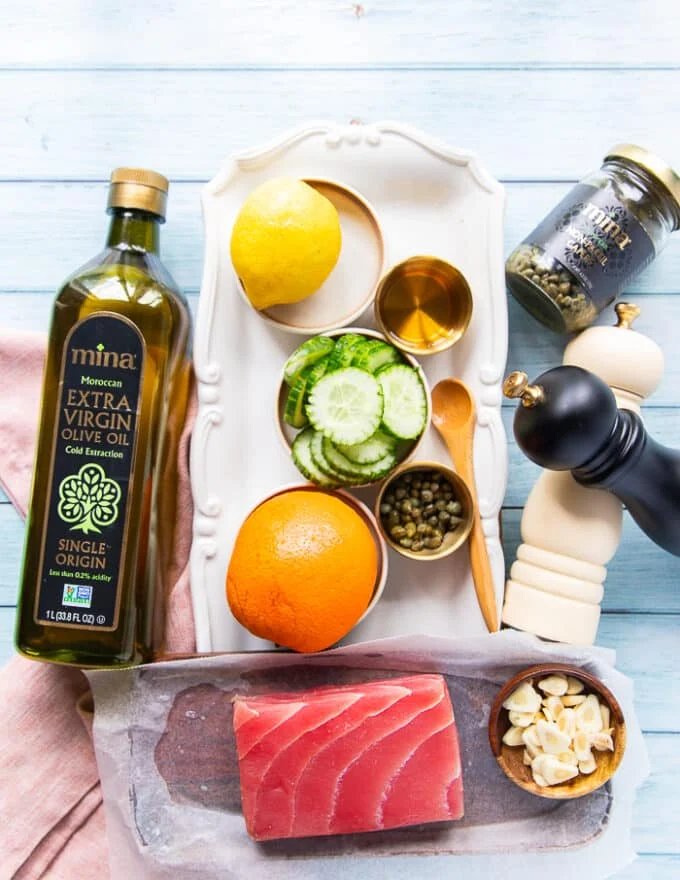ingredients for tuna crudo including fresh ahi tuna block,sliced cucumebrs, orange zest and juice, lemon zest and juice, quality olive oil, garlic chips, seasoning