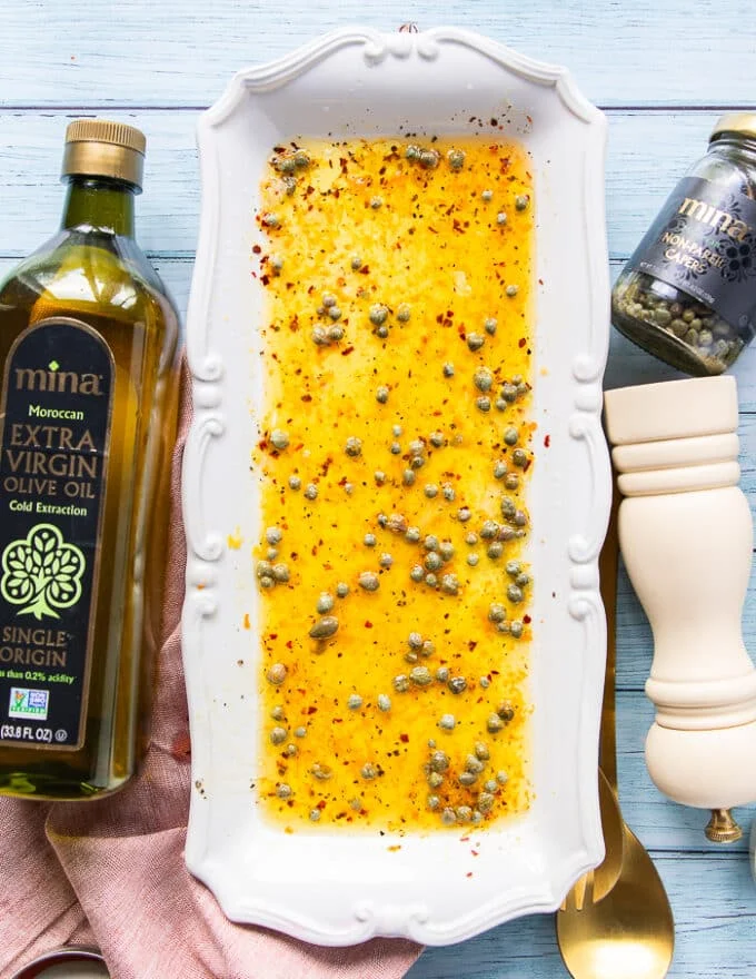 The remaining ingredients for the vinaigrette are added over the serving plate like olive oil, vinegar, capers, salt and pepper