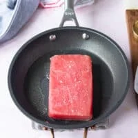 The seasoned Tuna placed in a hot skillet with neutral oil