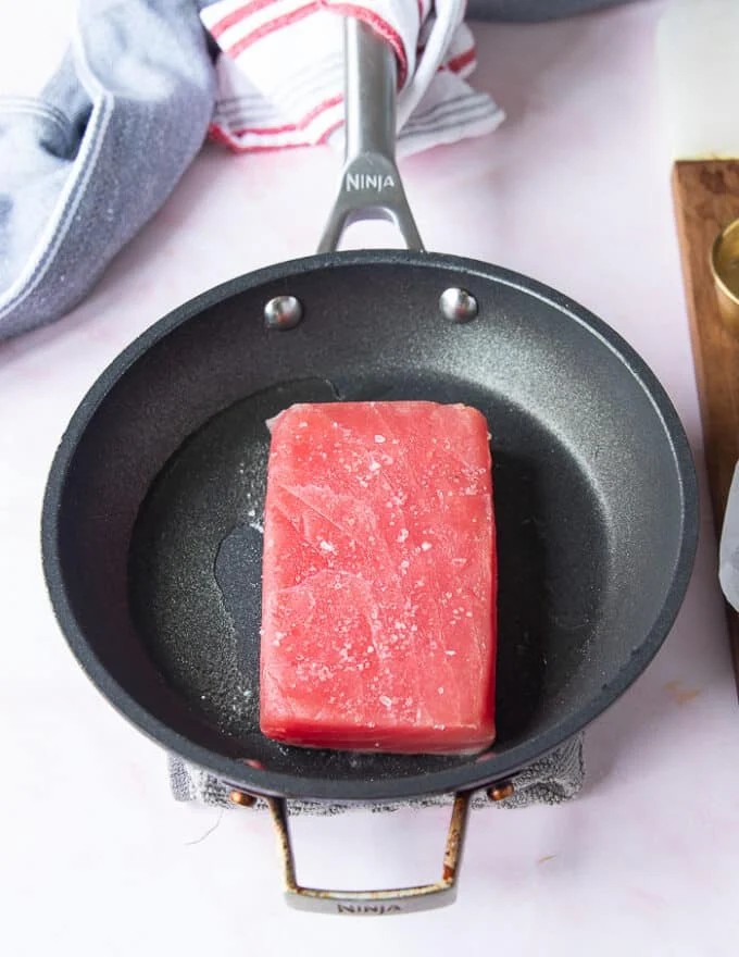 The seasoned Tuna placed in a hot skillet with neutral oil