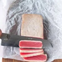 A sharp knife used to slice the tuna showing the beautiful pink raw inside of the ahi tuna